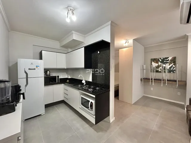 Foto de uma cozinha moderna com armários brancos e bancadas escuras.
