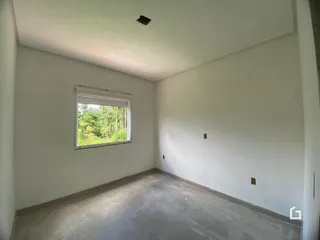 Ambiente interno com parede branca e janela de vista para a natureza.