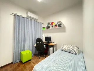 Quarto com cama e janela com cortinas azuis.