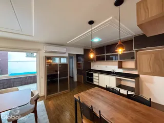 Ambiente interno de uma sala de estar com cozinha e sala de jantar em um imóvel.