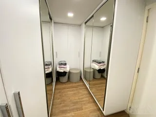 Hall de entrada com paredes brancas e piso de madeira.