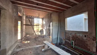 Interior de uma área em construção com paredes de concreto e tijolos expostos.