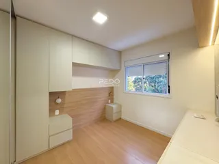 Ambiente interno de um cômodo com piso de madeira clara e armários brancos.