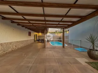 Vista de uma área externa com piscina e pátio coberto.