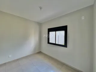 Vista interna de uma sala com paredes brancas e piso de cerâmica clara.