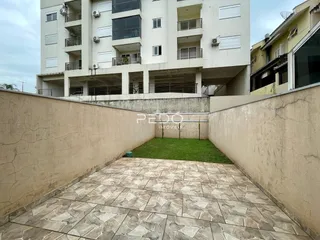 Vista de um pátio externo com piso de cerâmica e gramado entre muros