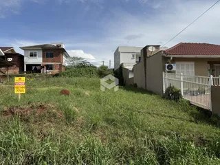 Vista externa de casas em Lajeado, Brasil, com terreno com vegetação alta.
