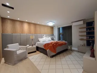 Quarto moderno com cama grande e painel de madeira na sala.