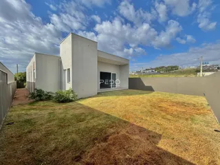 Fachada de uma casa moderna com jardim gramado e muro alto.