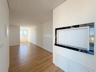 Corredor interno de uma residência com piso de madeira clara.