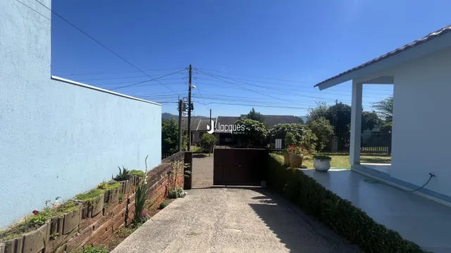 Fachada de uma residência em Lajeado, Brasil, com muro e portão de madeira.