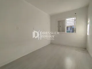 Foto de um cômodo interno vazio com paredes brancas e piso claro.