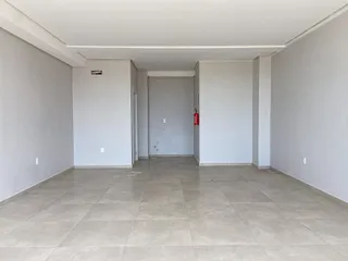 Foto de um corredor interno com paredes brancas e piso de cerâmica.