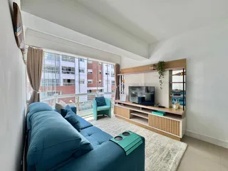 Sala de estar com sofá azul e uma grande janela.