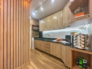 Cozinha moderna com armários de madeira clara e piso de madeira.