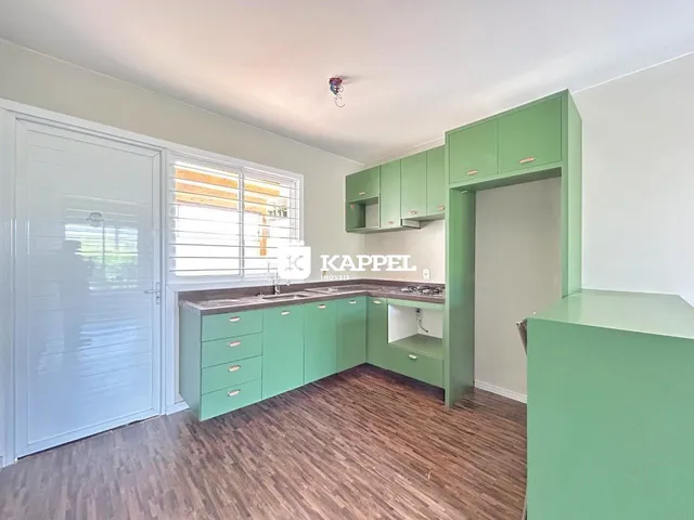 Cozinha com armários verdes e piso de madeira clara.