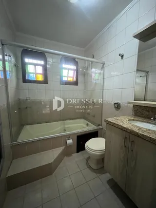Foto de um banheiro com box de vidro e piso cerâmico.