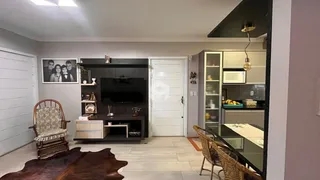 Sala de estar com piso de madeira clara e móveis escuros.