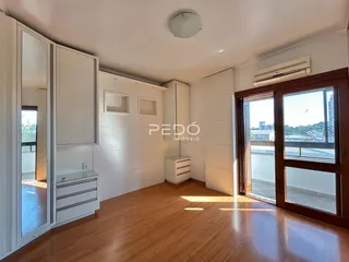 Sala de estar com piso de madeira e armários brancos em um imóvel em Lajeado.