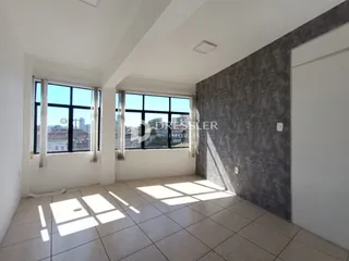 Vista interna de uma sala com grandes janelas e piso de cerâmica.