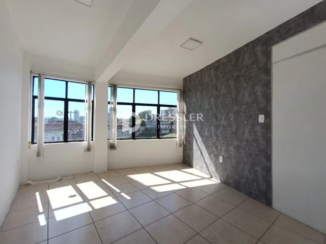 Vista interna de uma sala com grandes janelas e piso de cerâmica.