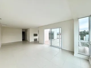 Sala ampla com piso claro e porta de vidro que dá acesso a uma área externa.