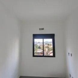 Foto de uma parede branca com uma janela que oferece uma vista externa.
