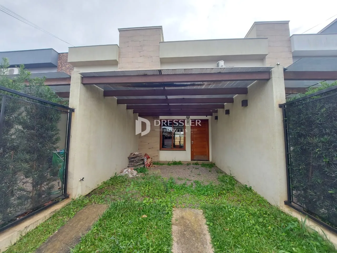 Vista da fachada de uma residência com jardim e cerca.