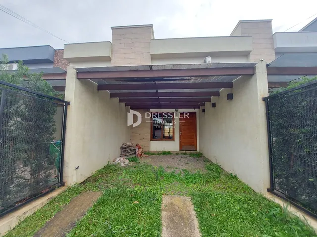 Vista da fachada de uma residência com jardim e cerca.