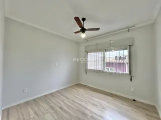 Ambiente interno de uma sala com piso de madeira clara e paredes brancas.