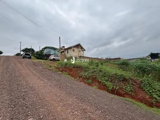 Vista da estrada de terra que sobe em direção a casas na paisagem.