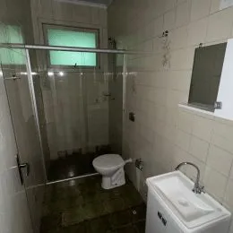 Foto interna de um banheiro com louças sanitárias e revestimento de azulejos brancos.