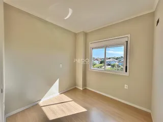 Vista interna de um cômodo com piso de madeira clara e janela.