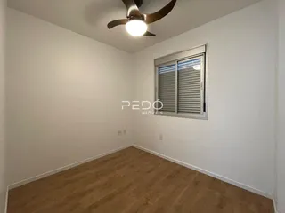 Ambiente interno de uma sala com piso de madeira clara e janela.