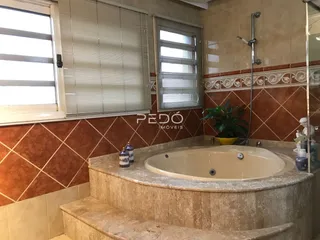 Foto de um banheiro com banheira embutida em pedra e revestimento de azulejos.