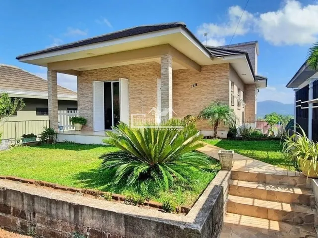 Fachada de uma casa em Lajeado, Brasil, com jardim frontal e muro de contenção.