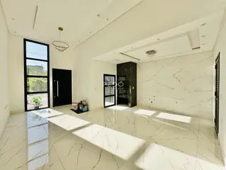 Sala de estar ampla com piso de mármore claro e paredes brancas.