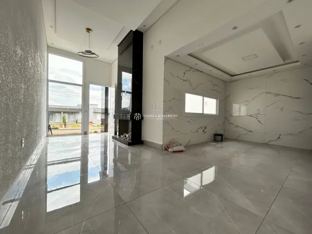 Sala de estar ampla com piso de porcelanato polido e grandes janelas.