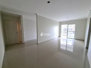 Interior de uma sala ampla com piso claro e paredes brancas.
