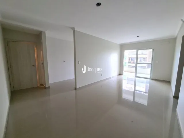 Interior de uma sala ampla com piso claro e paredes brancas.