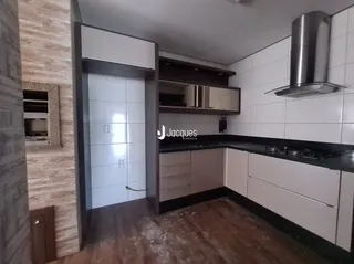Interior de uma cozinha com armários brancos e bancada escura.