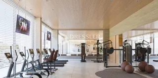 Corredor interno de uma residência moderna com piso claro e grandes janelas.