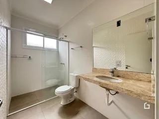Foto interna de um banheiro com piso de cerâmica e box de vidro.
