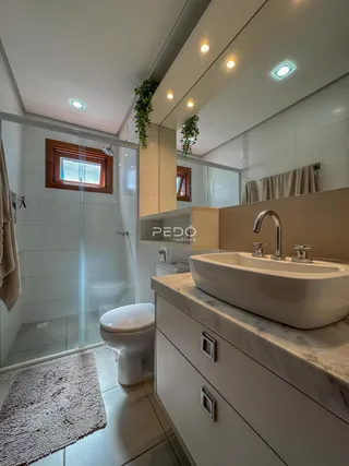 Banheiro com box de vidro e bancada moderna.