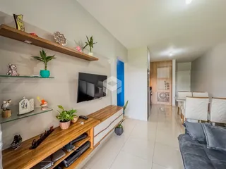 A sala de estar possui prateleiras de madeira e uma televisão montada na parede.