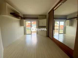 Sala de estar ampla com piso de madeira clara e acesso a área externa.