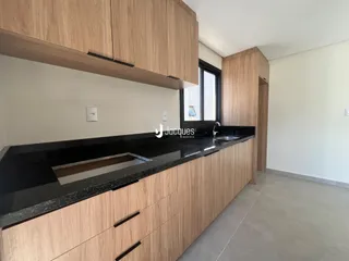 Cozinha moderna com armários de madeira clara e bancada escura.