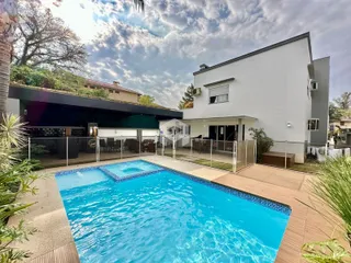 Foto da fachada de uma residência com piscina e área externa.