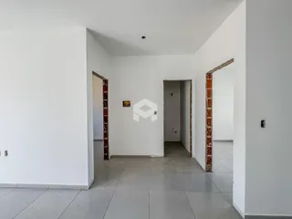 Hall de passagem com paredes brancas e detalhes em tijolo aparente.