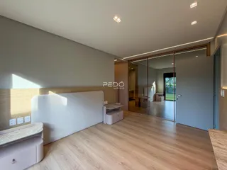 Quarto com piso de madeira clara e cabeceira em painel na sala de um imóvel.